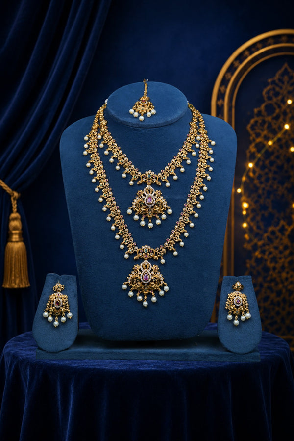 Gold necklace and earrings set on a blue velvet stand with a dark blue curtain background